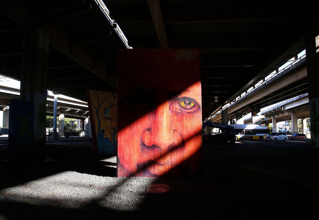 Afternoon sunlight pouring between spans of Interstate 345 lights up murals between Canton...