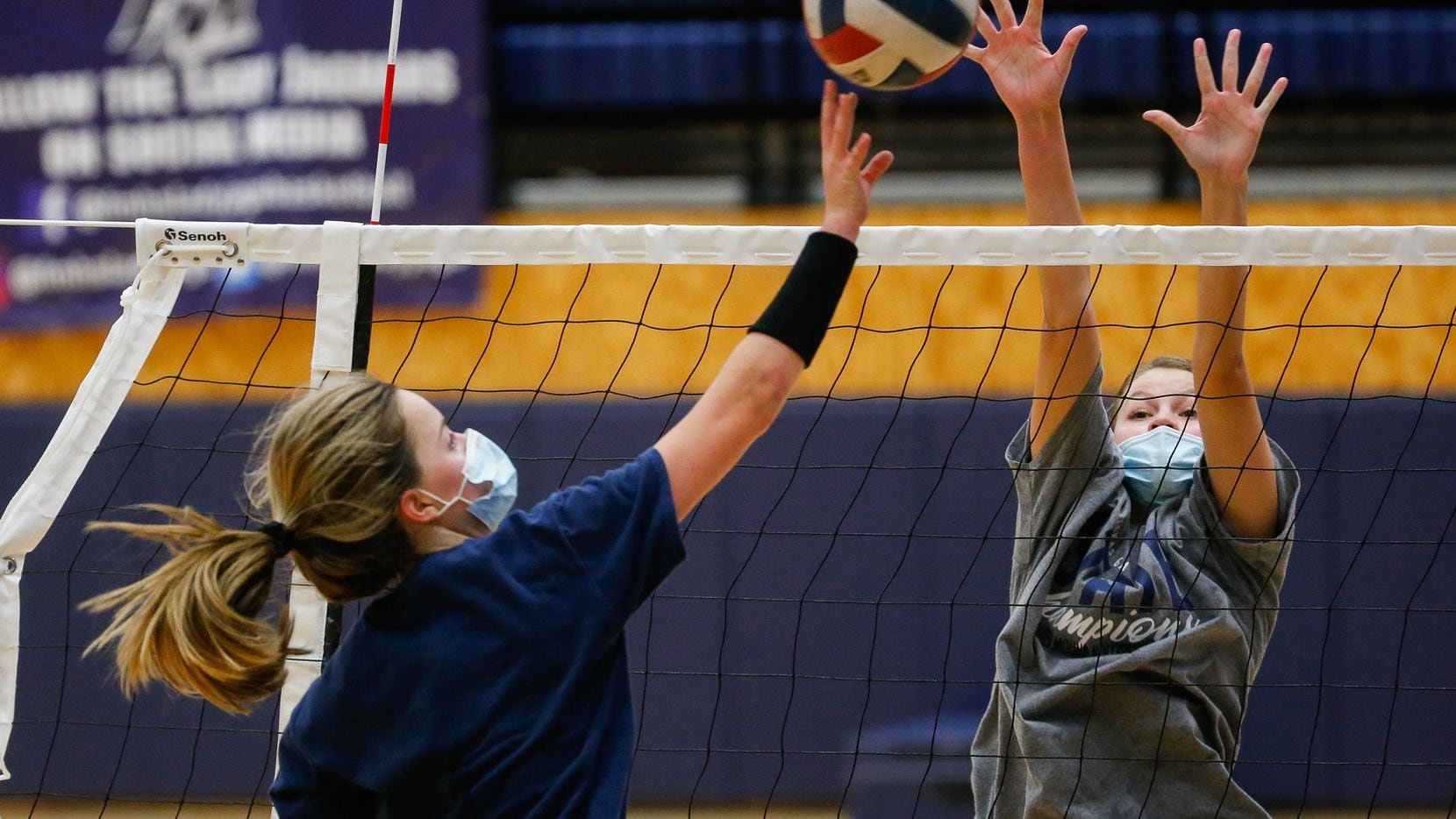 Flower Mound High School volleyball player Gabby Walker (right) goes up to block the ball...