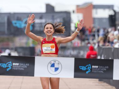Megan Taylor raises her arms as she crosses the BMW Dallas Marathon finish line on Sunday,...
