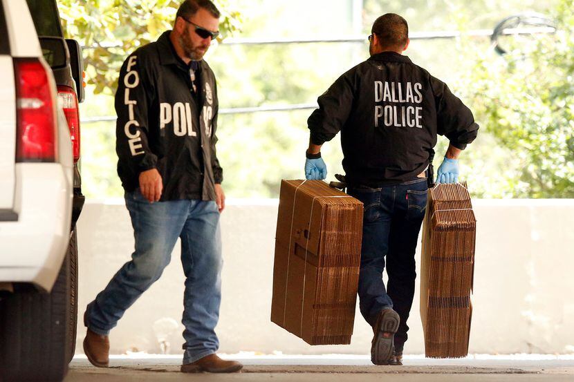 Dallas police officials carry cardboard boxes into the Catholic Diocese of Dallas as they...