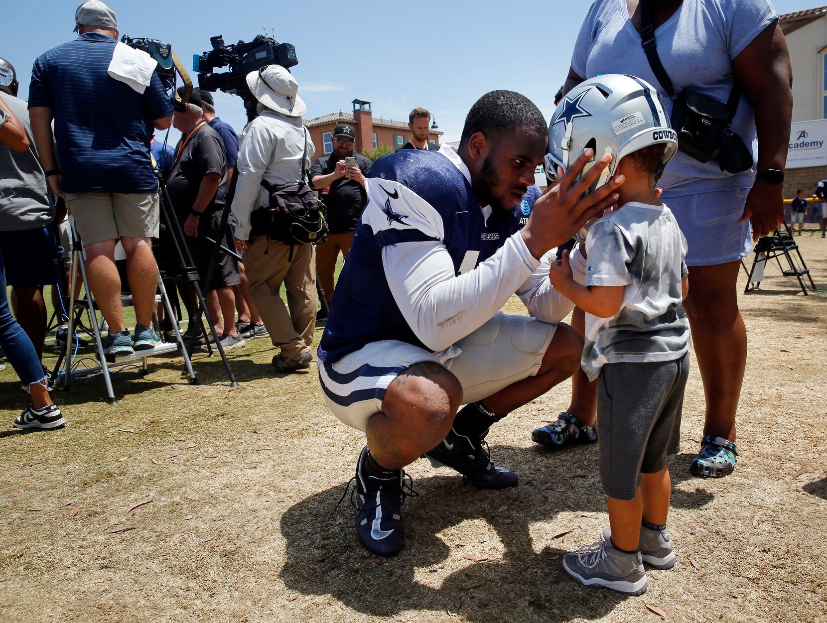 Dallas Cowboys outside linebacker Micah Parsons puts his helmet on his son Malcolm following...