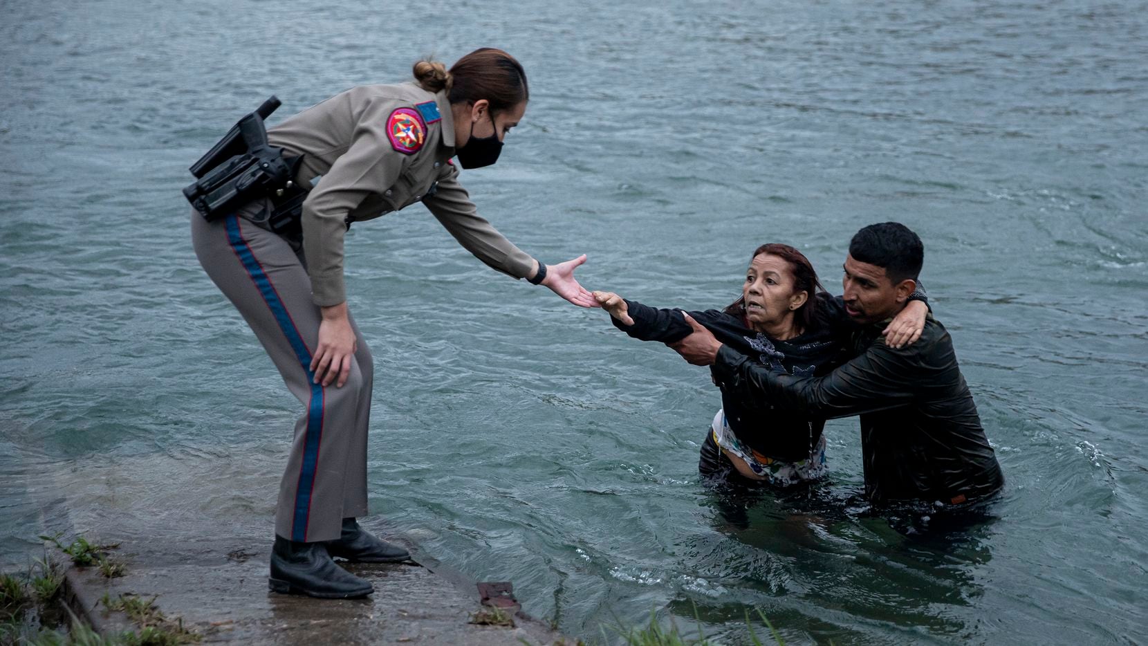 A Texas Department of Public safety trooper helps Belkis Salas of Venezuela out of the Rio Grande near Del Rio on Friday, April 30, 2021. Salas struggled to cross the river, falling halfway through and being pulled up by her son-in-law and a smuggler. Many Venezuelans are being welcomed for asylum processing on one part of the border while Central Americans are being quickly expelled on other parts of the border.