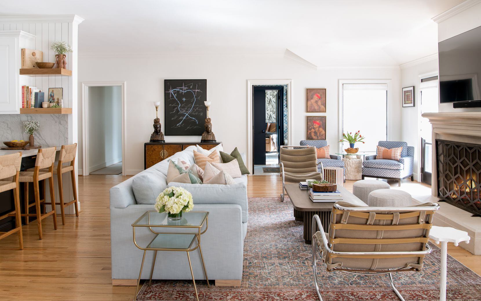 A living room features a blue sofa with antique lounge chairs and a warm fireplace.