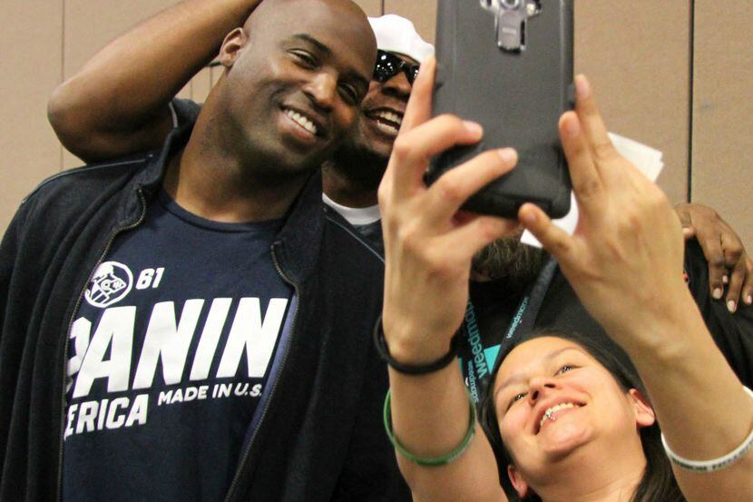 Fans get a cellphone photo with former NFL player Ricky Williams (left).