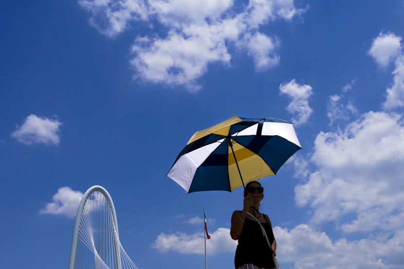 Vimarie Rivera shields herself from the sun under an umbrella as she walks on the Ronald...