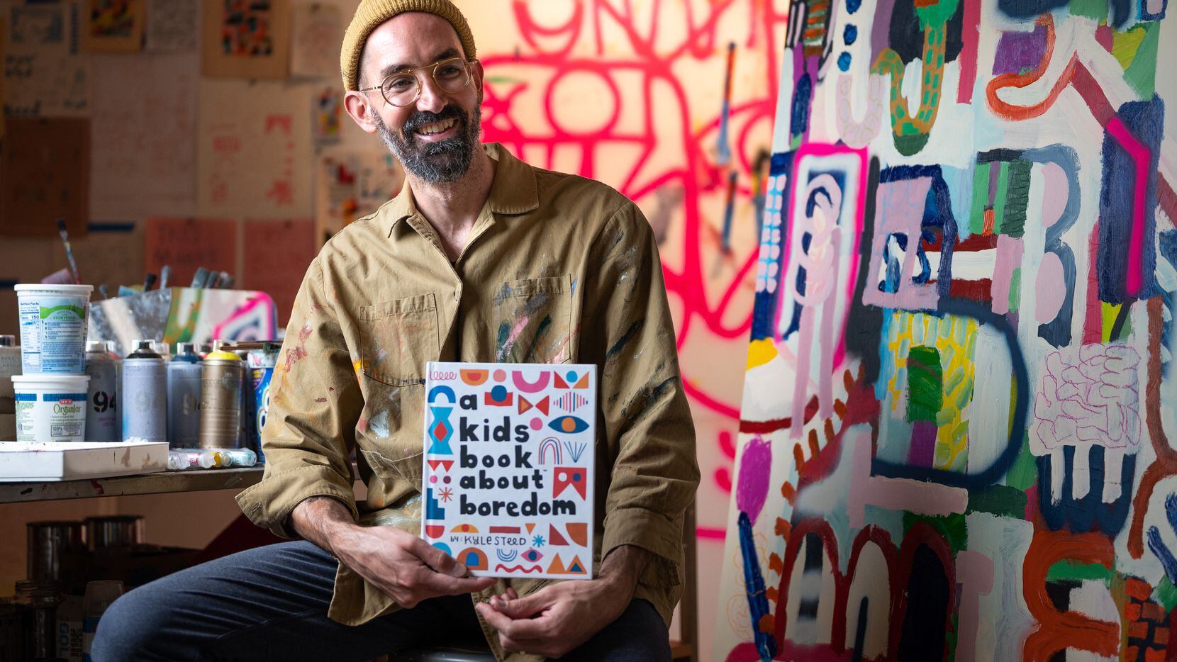 Artist Kyle Steed with his book, A Kids Book About Boredom, at his art studio in Dallas, on Nov. 16, 2021.