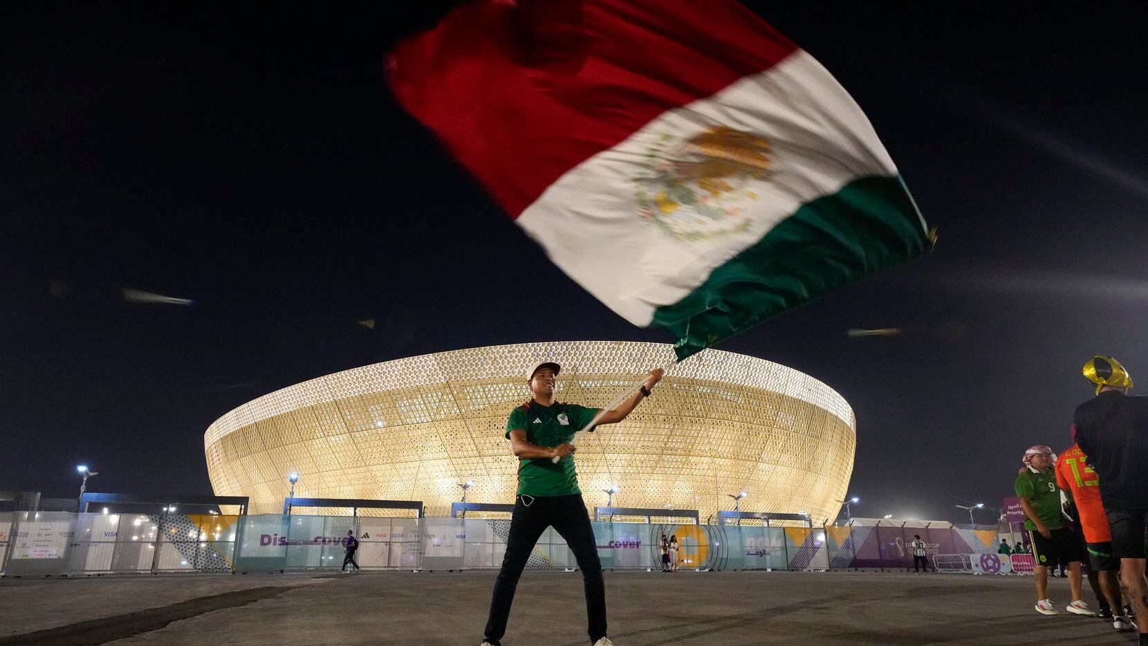 Luis Radilla, de Acapulco, México, ondea una bandera afuera del Estadio Lusail antes del...
