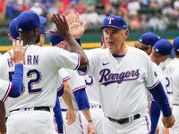 Texas Rangers manager Bruce Bochy high fives relief pitcher Taylor Hearn (52) before the...