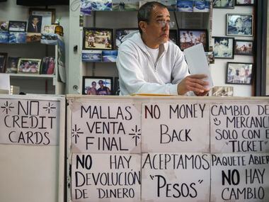 Downtown El Paso business owner Gustavo Tavera looks up to passing by shoppers while paying...