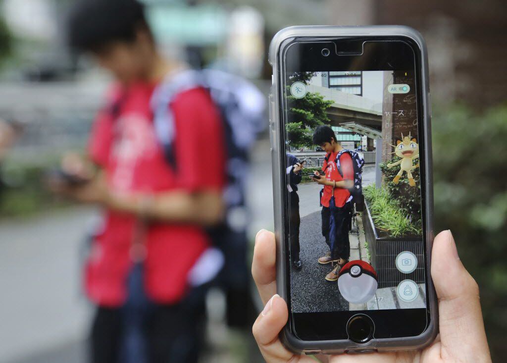 FILE - In this July 22, 2016 file photo, Japanese students play "Pokemon Go" in the street...