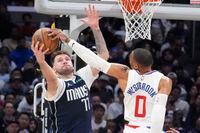 Dallas Mavericks guard Luka Doncic, left, grabs a rebound away from Los Angeles Clippers...