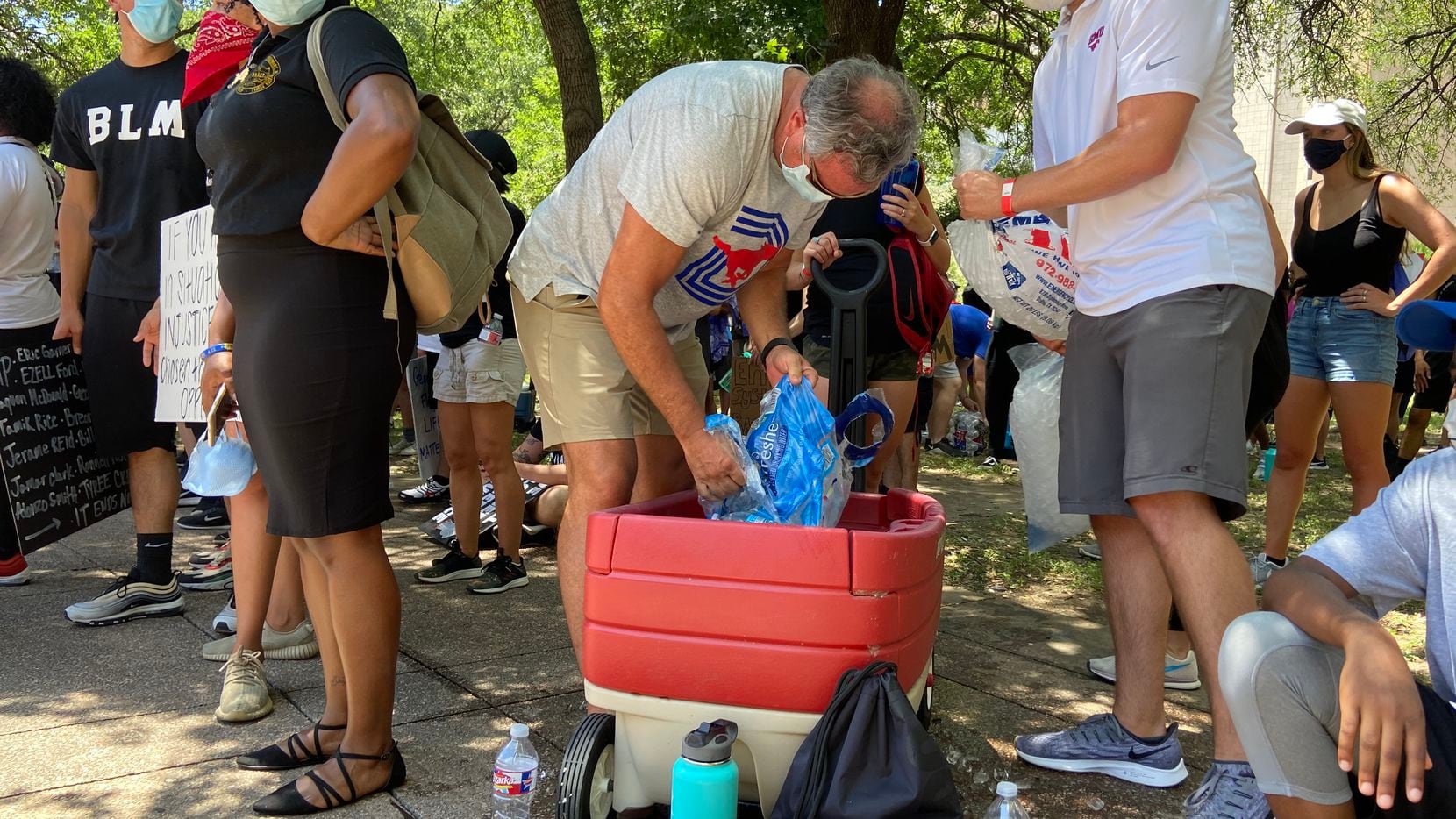 SMU football coach Sonny Dykes passes out water bottles while attending a protest at Dallas...