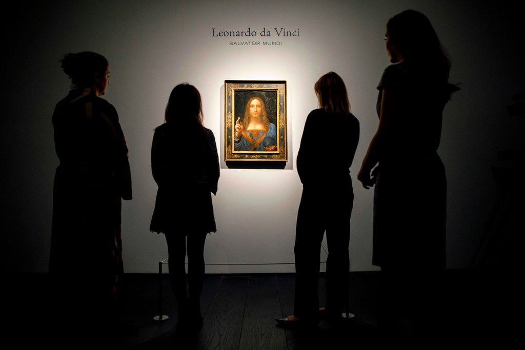 Christie's employees pose in front of a painting entitled Salvator Mundi by Italian polymath...