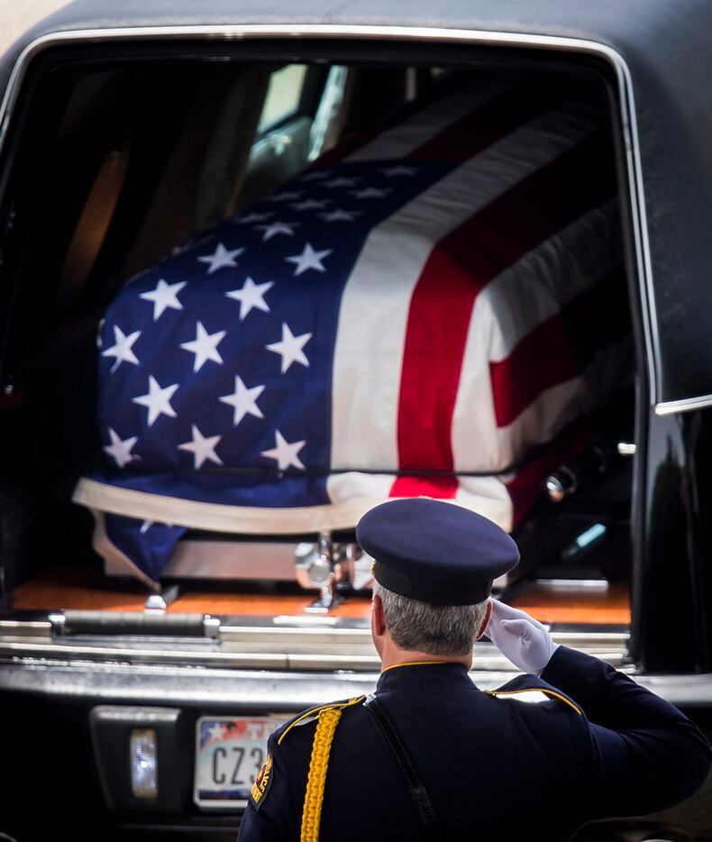 A member of the DPD honor guard salutes the flag draped casket Dallas police officer Michael...