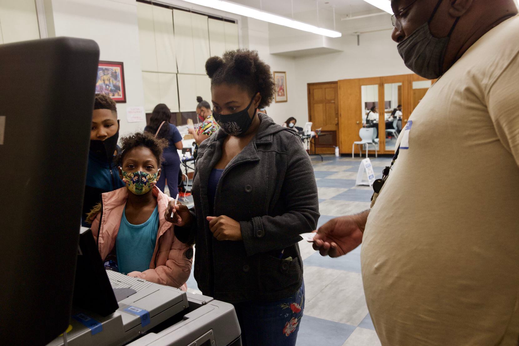 Krystal White (center) casts a ballot in the general election as her children Perell (left)...