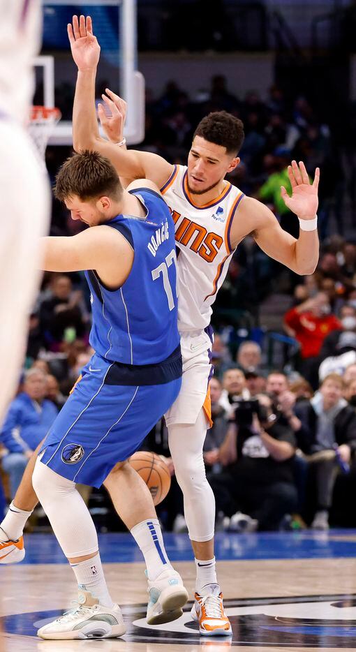 Dallas Mavericks guard Luka Doncic (77) gets tangled up with Phoenix Suns guard Devin Booker...