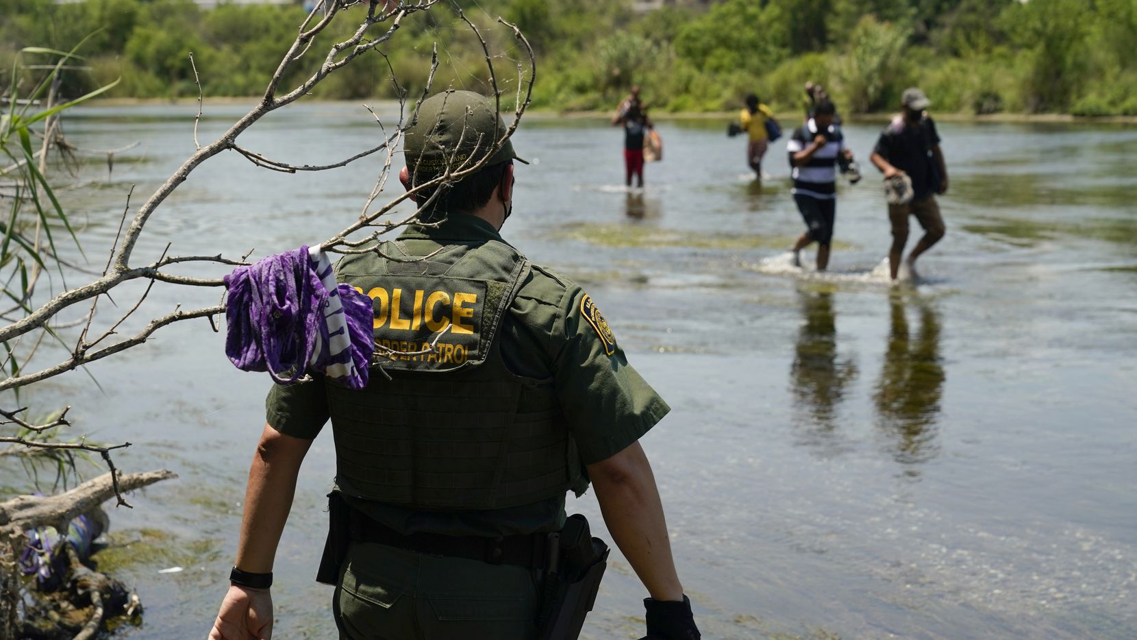 Un agente de la Patrulla Fronteriza de Estados Unidos observa a un grupo de migrantes cruzar...