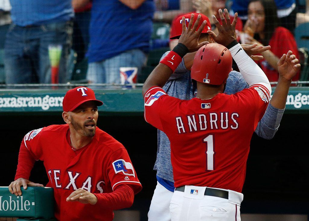 Texas Rangers manager Chris Woodward congratulates Elvis Andrus (1) after he scored against...