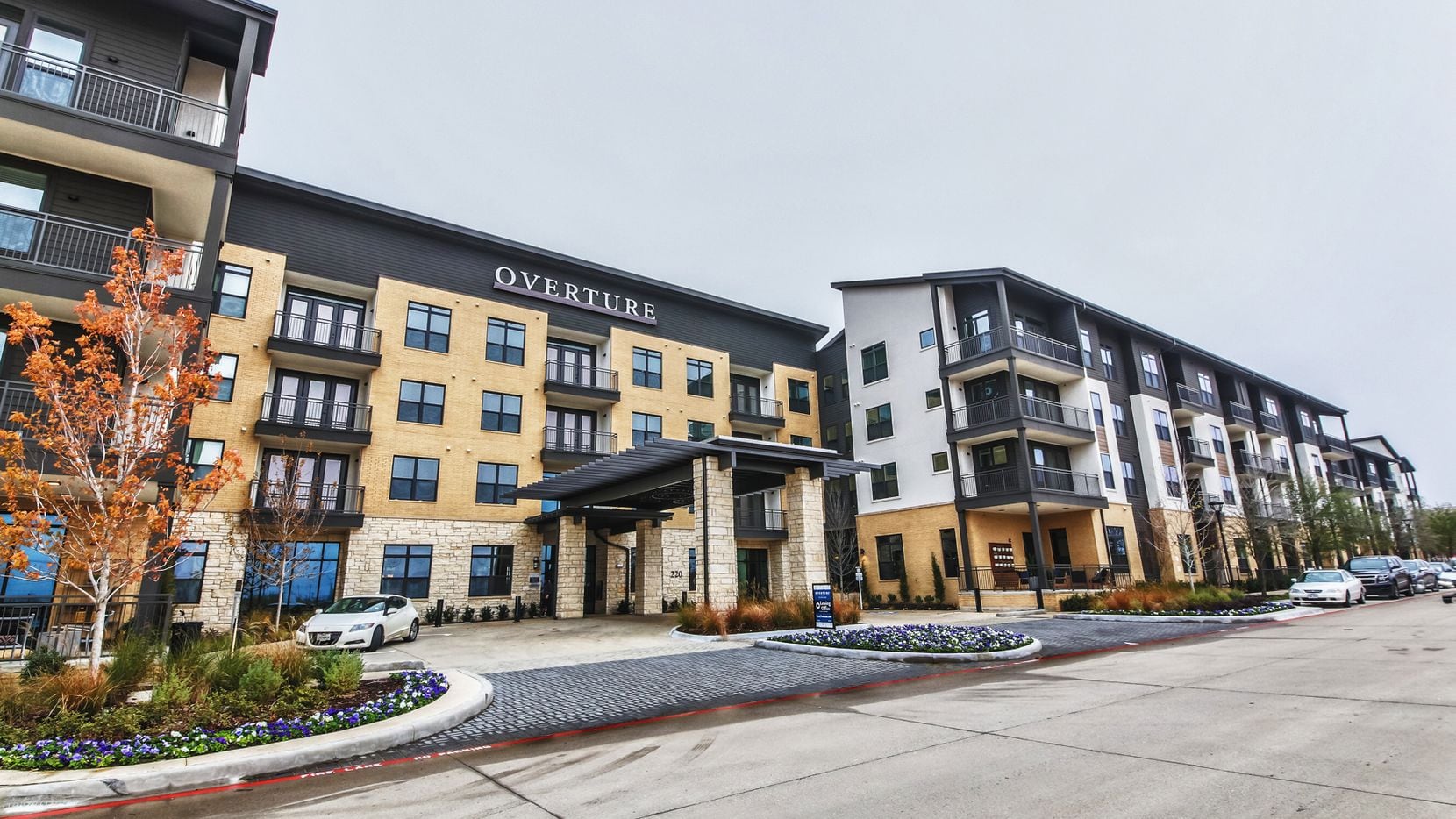 A four-story apartment complex called Overture Fairview with a yellow and gray exterior.