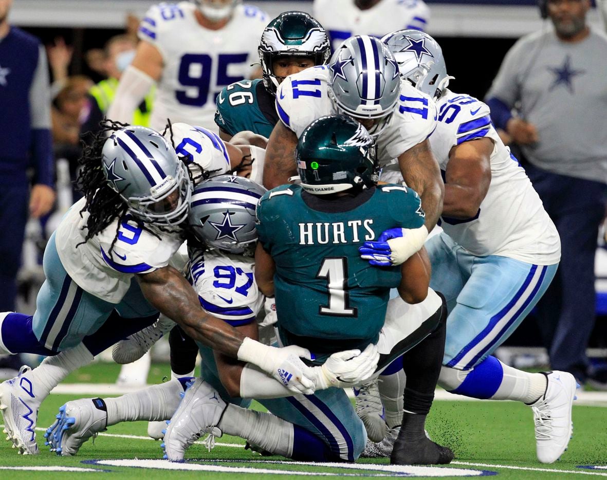 Philadelphia Eagles quarterback Jalen Hurts (1) is swarmed by Dallas Cowboys defenders, including middle linebacker Jaylon Smith (9); defensive tackle Osa Odighizuwa (97), and linebacker Micah Parsons (11) during the second half of a NFL football game at AT&T Stadium in Arlington on Monday, September 27, 2021. (John F. Rhodes / Special Contributor)