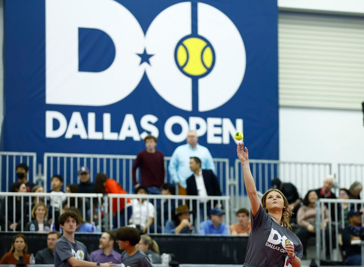 A ball girl tosses a tennis ball to fans during the finals of the ATP Dallas Open between...