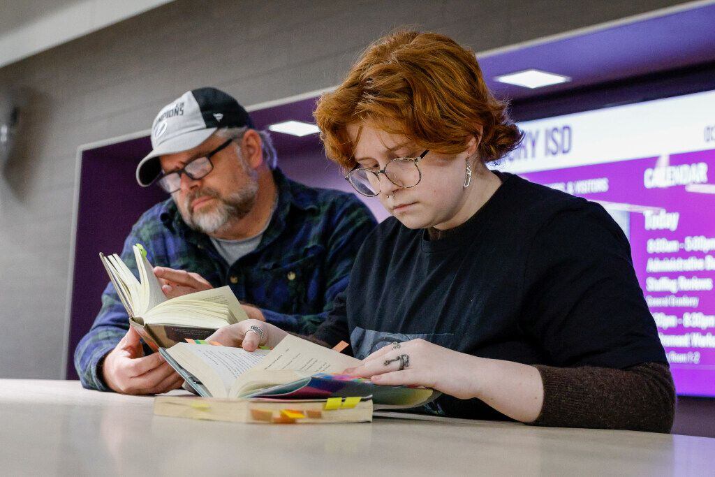 Granbury High School junior Lou Whiting, 17 (right), looks over a book with their father...