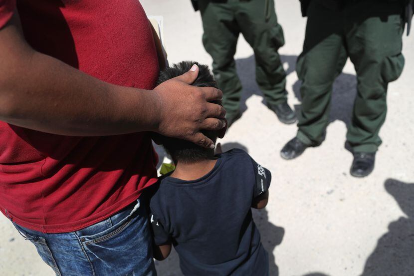 Un agente de la Patrulla fronteriza interroga a un padre de Honduras y su hijo cuando...