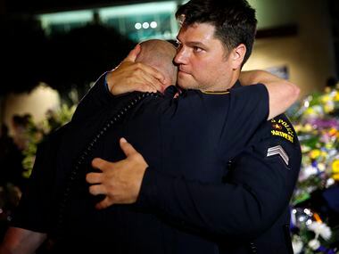 Dallas Police Department officers are overcome with emotion as they visit a memorial in...