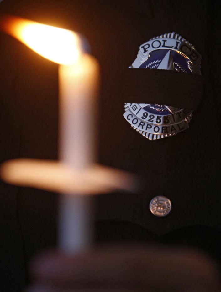 A police officer holds a candle in memory of police officers during a candlelight vigil hosted by the Dallas Police Association at Dallas City hall in Dallas, TX July 11, 2016. (Nathan Hunsinger/The Dallas Morning News)
