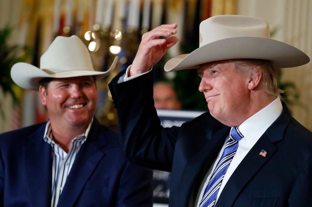 President Donald Trump tries on a Stetson hat, as Dustin Noblitt, with Stetson Hats, smiles,...