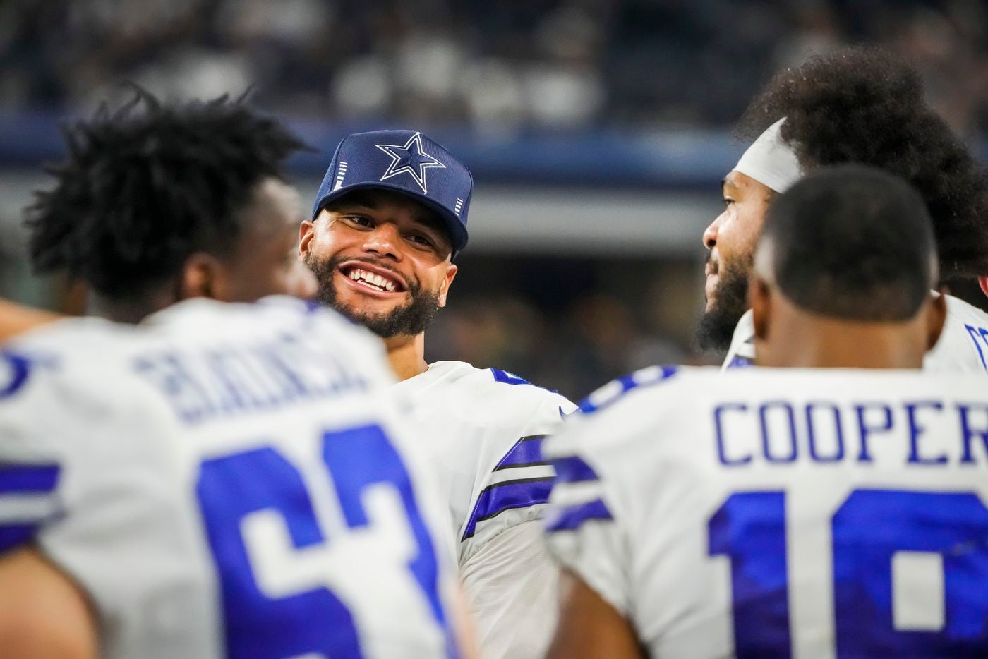 Dallas Cowboys quarterback Dak Prescott laughs on the bench with offensive tackle La'el Collins (71), wide receiver Amari Cooper (19) and center Tyler Biadasz (63) during the second half of an NFL football game against the Washington Football Team at AT&T Stadium on Sunday, Dec. 26, 2021, in Arlington. The Cowboys won the game 56-14.