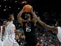 Miami forward Norchad Omier drives between Houston forward Reggie Chaney, left, and guard...