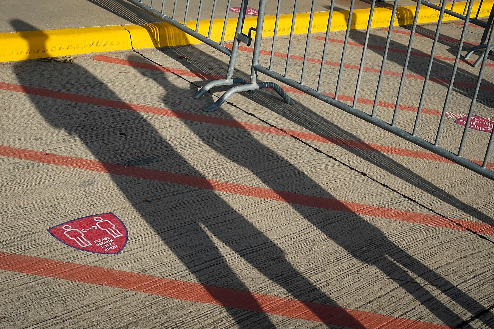 Jeff Files and his son Bentley. 9, cast shadows across social distancing markers are the first in line to enter the West Gate before an MLS soccer game between FC Dallas and Nashville SC at Toyota Stadium on Wednesday, Aug. 12, 2020, in Frisco, Texas. (Smiley N. Pool/The Dallas Morning News)