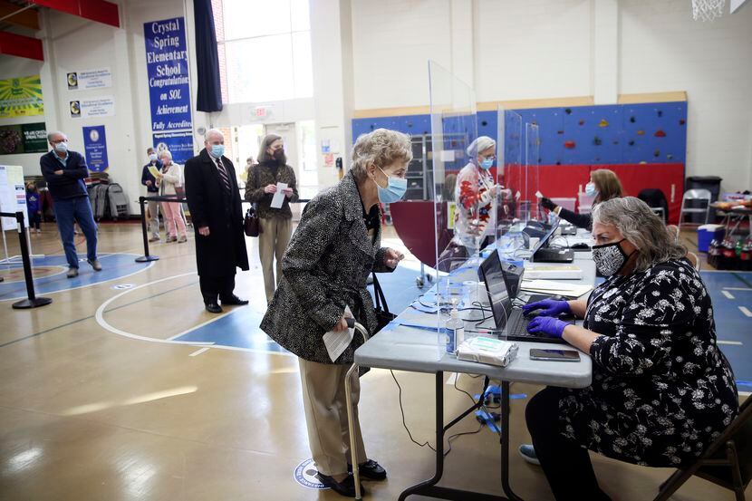 Betty Holland, de 76 años, a la izquierda, se registra para votar con la funcionaria...
