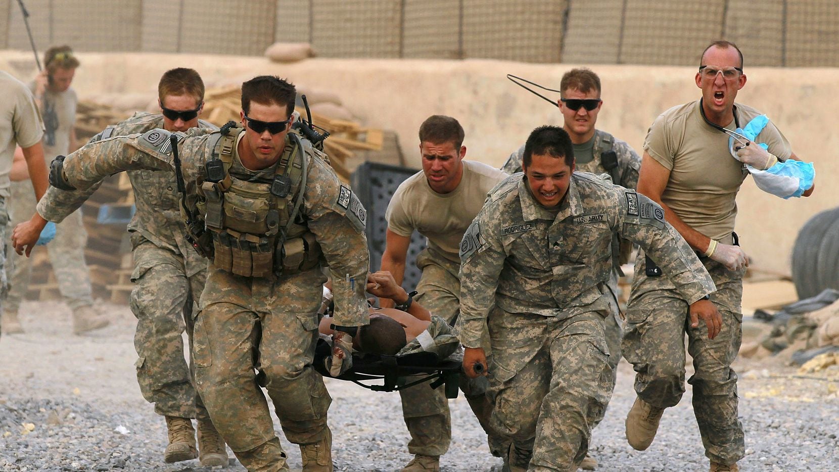 U.S. Army soldiers carry a critically wounded American soldier on a stretcher to an awaiting...
