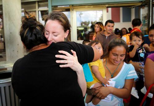La voluntaria Claire Scoville recibe un abrazo de una madre hondureña en la estación de...