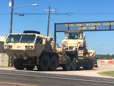Heavy equipment rolls out of one of the gates to Texas Army Nation Guard Camp Swift outside...