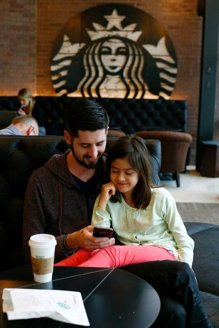 Samuel Bistrian and his daughter Emma Bistrian, 7, look at a phone at the new Starbucks in...