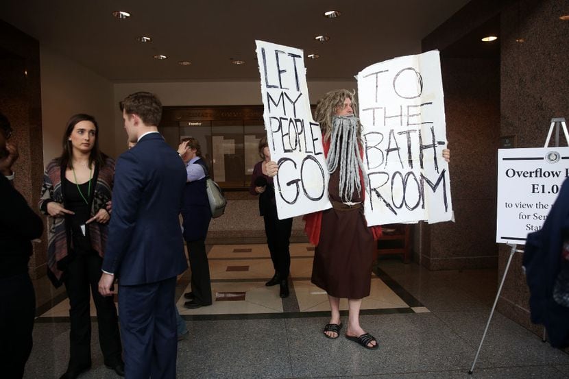 John Erler, dressed as Moses, holds signs as members of the Senate State Affairs Committee...