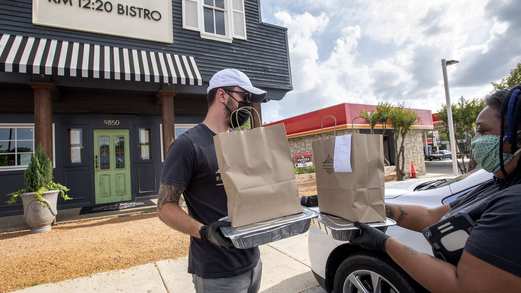 Tyler Bartlett and Kathleen Mathis, servers at RM 12:20 Bistro, deliver a curbside order to...