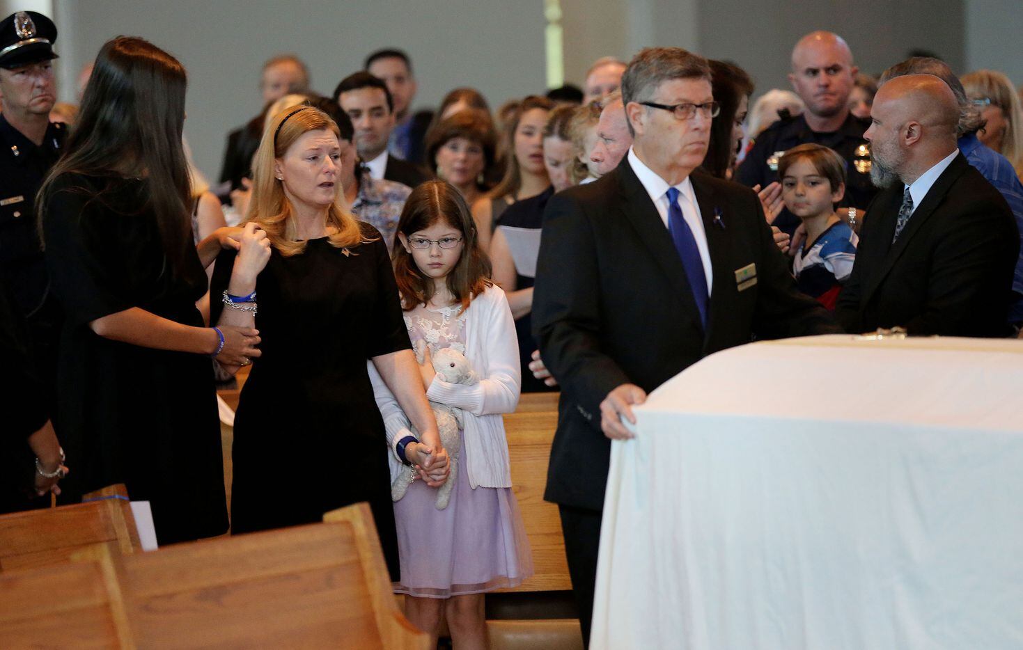 Heidi Smith (second to left) embraces her daughters, Victoria (left) and Caroline Smith (center), during the funeral for her husband, Dallas police sergeant Michael Smith.