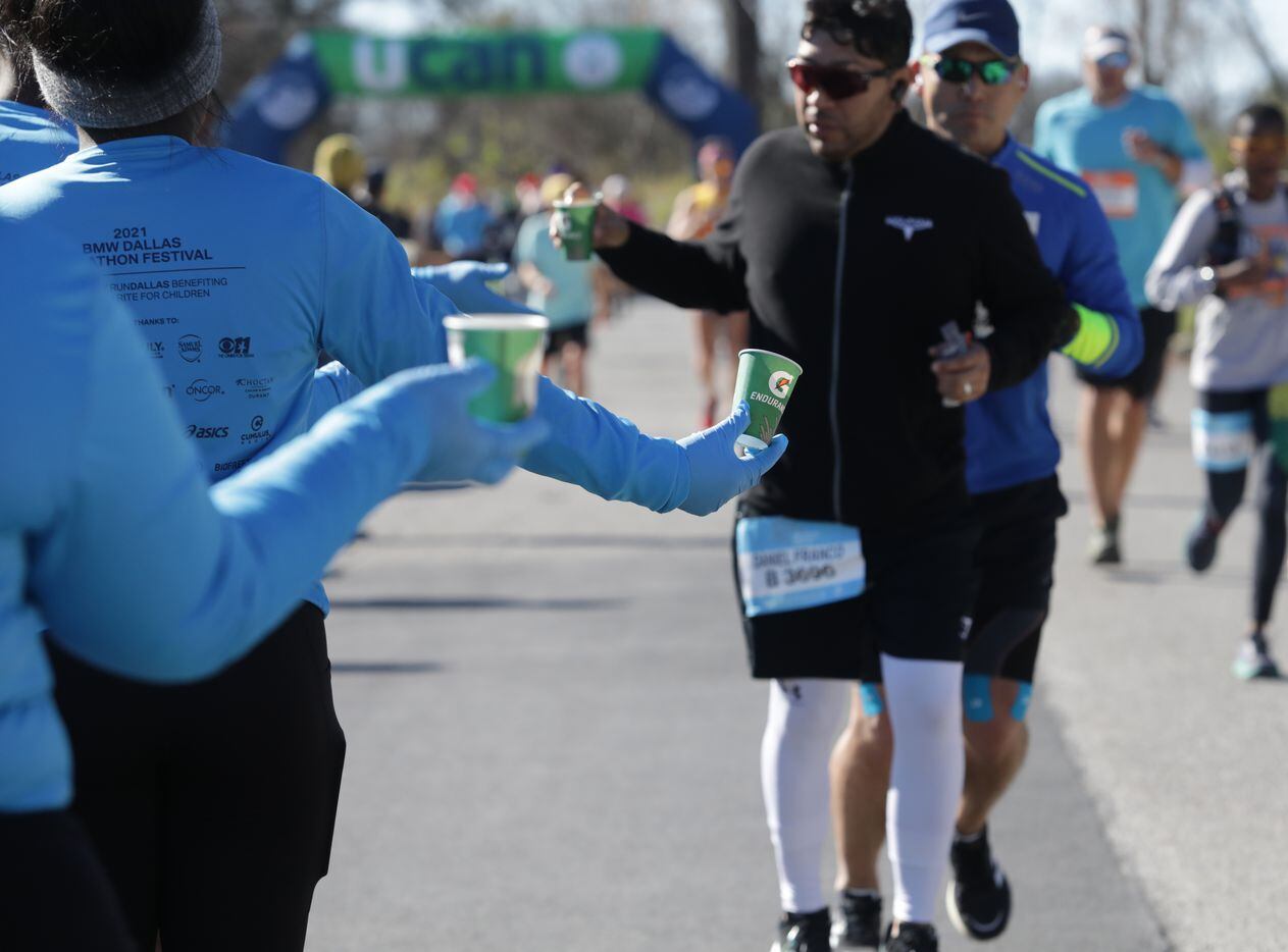 Runners pass a water station during the BMW Dallas Marathon at White Rock Lake in Dallas,...