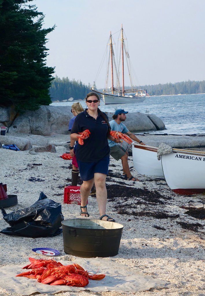 Assistant cook Sarah Collins strolls the beach offering lobsters to eat; there were 40 of...