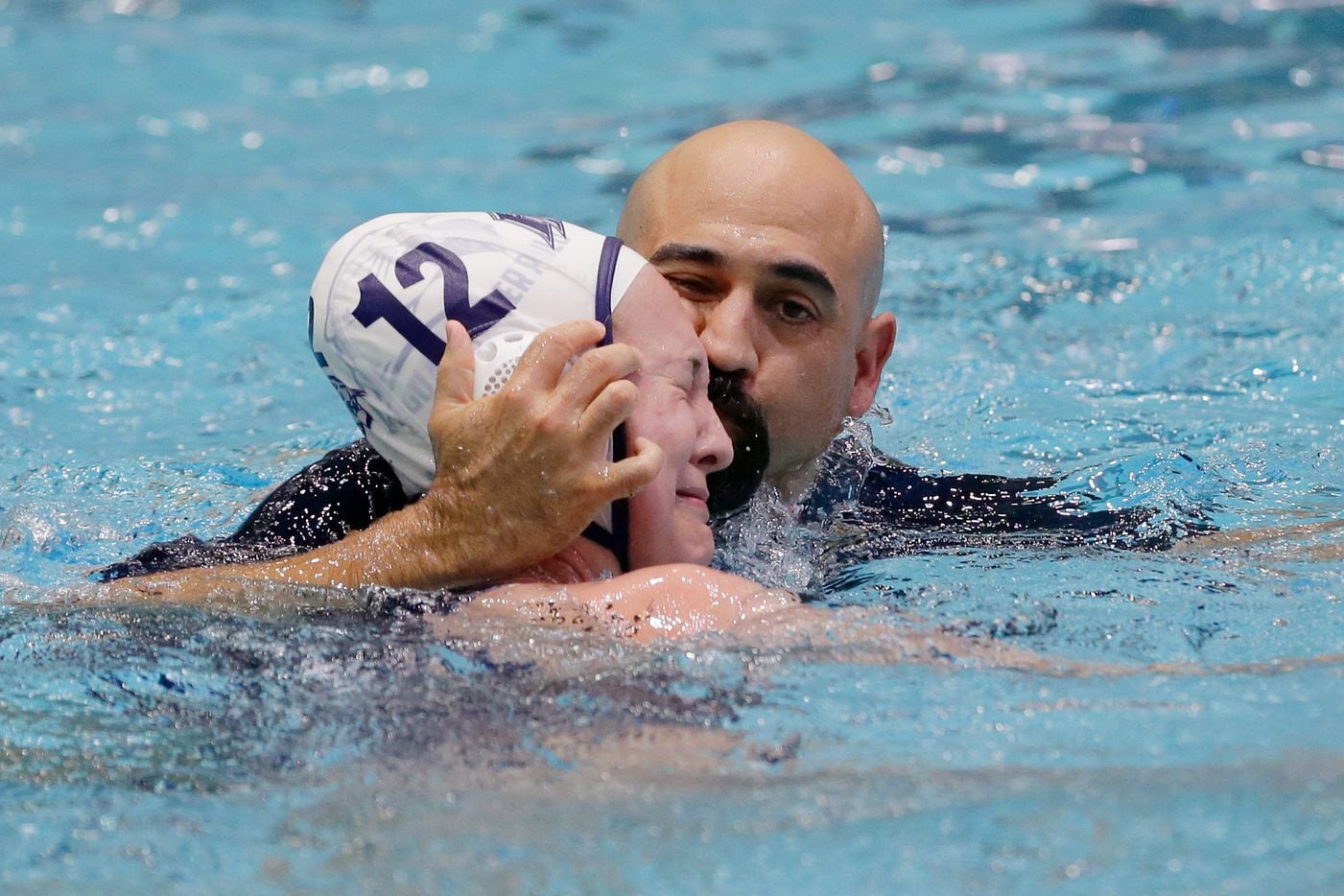 Flower MoundÕs Ava Pawlik (12) is kissed in the water by her father and head coach Karl...