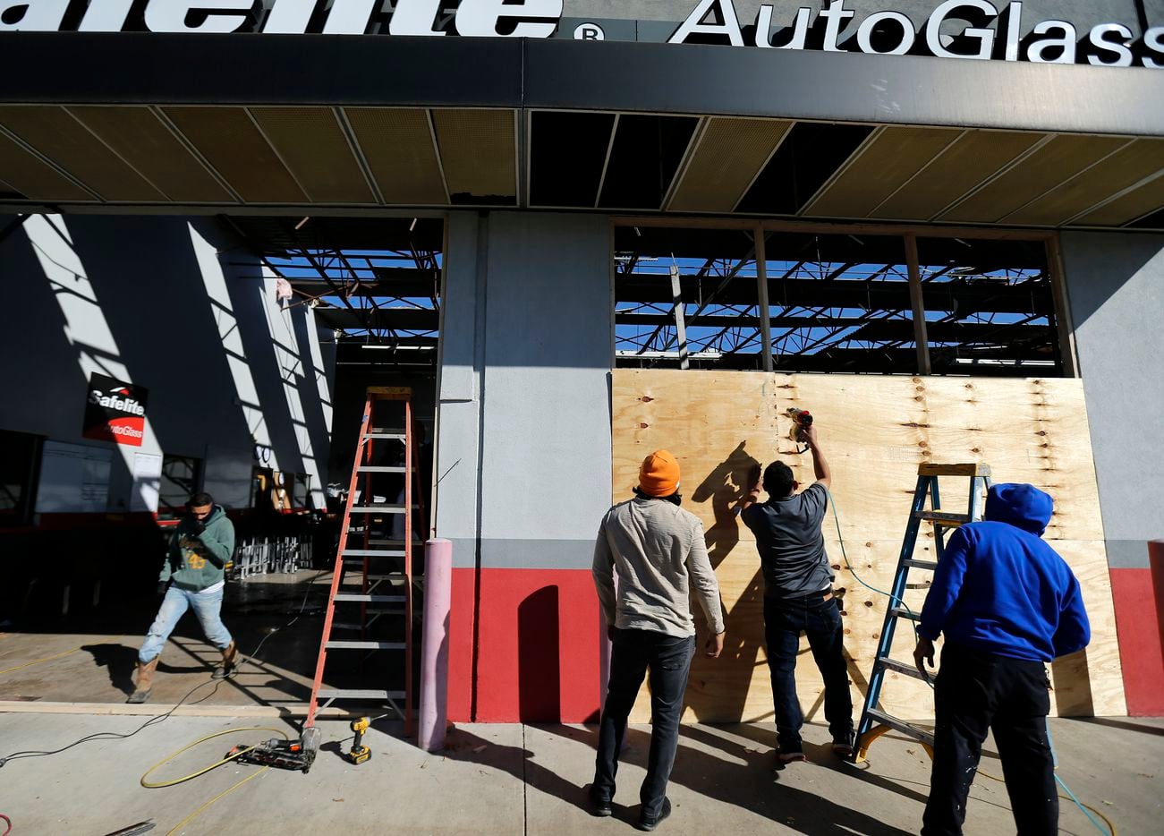 The crew from Remodel One board up the Safelite Auto Glass shop on S. Cooper St., Wednesday, November 24, 2020, after it was damaged in the tornado-warned storm Tuesday evening.