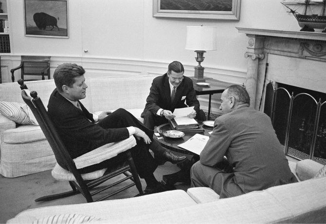 John F. Kennedy sits in his favorite rocking chair in his office during a meeting with...