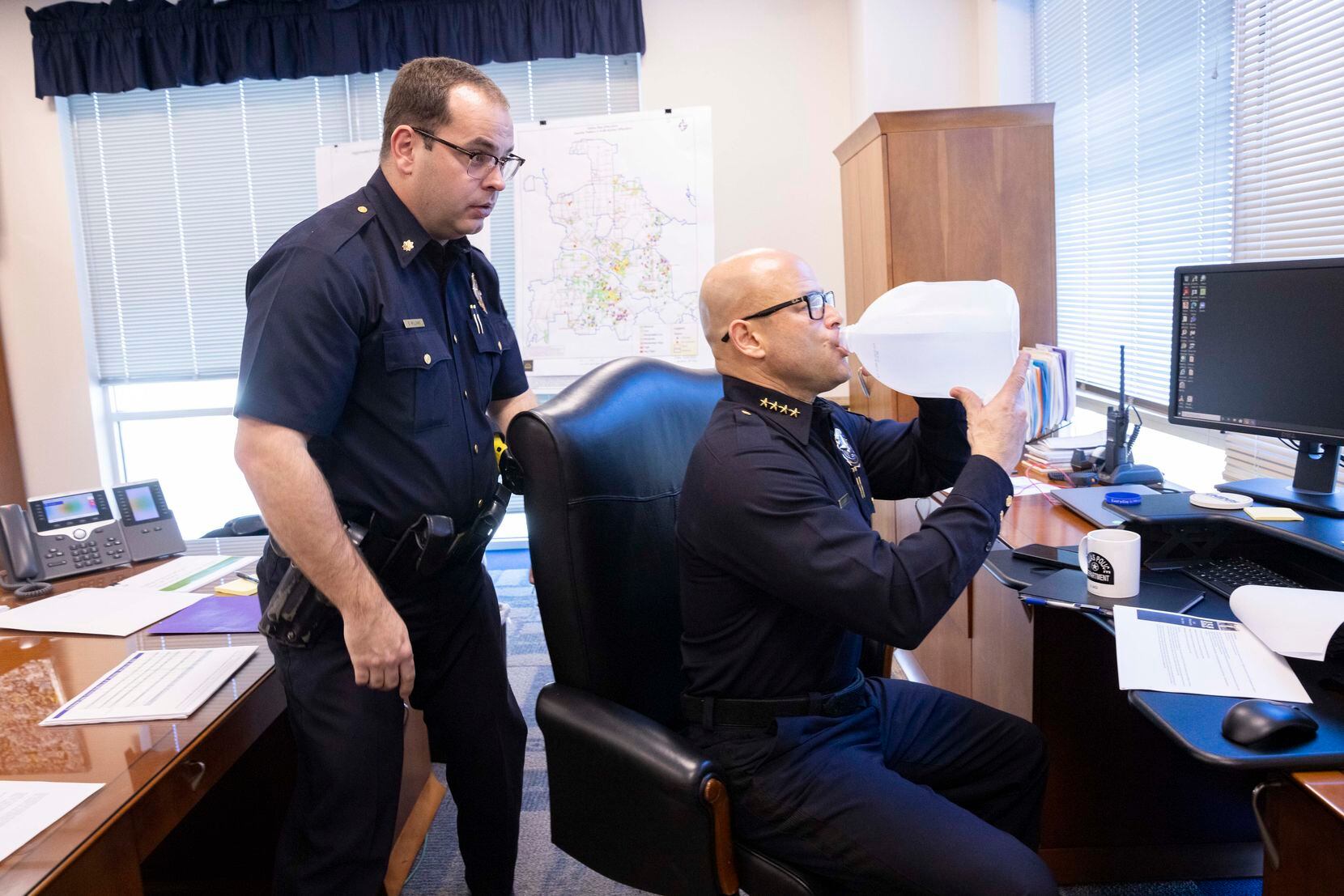 Dallas police Chief Eddie García drinks his gallon of water as Major Stephen Williams helps check García’s webcam before a video meeting with his command staff at Jack Evans Police Headquarters on Tuesday, Jan. 25, 2022, in Dallas, TX. 