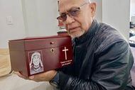 Santos Cumana holds the urn with the ashes of his son, Elio David Cumana Rivas, on August 4,...