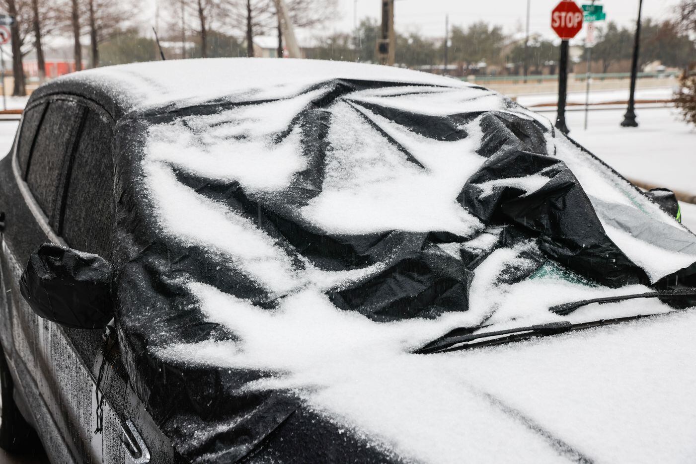 A car is covered with a windshield snow cover as sleet falls over the Dallas metroplex on...