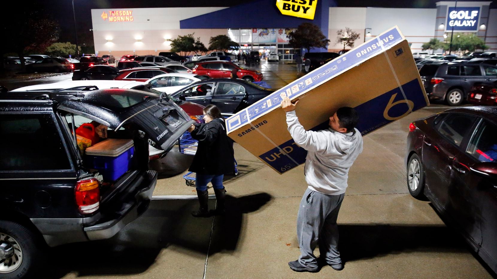 Thanksgiving Day shopper Jose Bazaldua of Dallas loads a 65-inch flat screen television into...